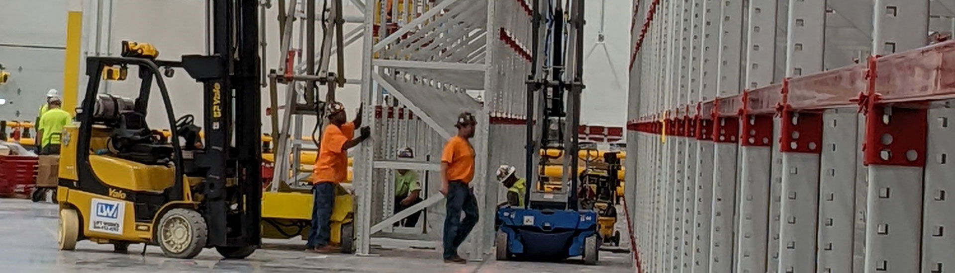 Carpenters working around scaffolding within a large warehouse